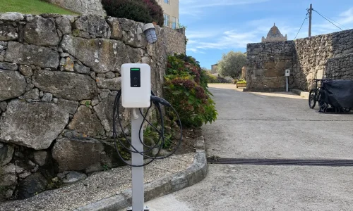 Punto de recarga para vehículo eléctrico instalado sobre pedestal en un establecimiento turístico en Galicia